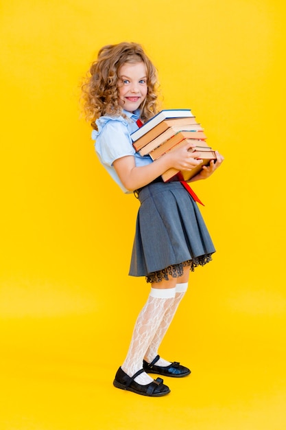 Portrait d'une écolière tenant une lourde pile de livres, préparation aux examens, collège,