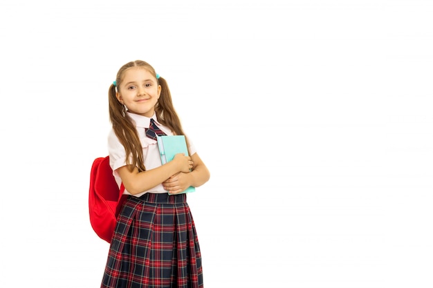 Portrait d'une écolière en uniforme debout sur fond blanc