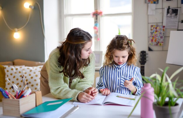 Portrait d'écolières sœurs apprenant en ligne à l'intérieur à la maison, concept de coronavirus.