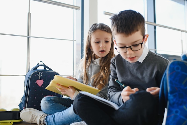 Portrait d'écoliers souriants dans le couloir de l'école avec des livres