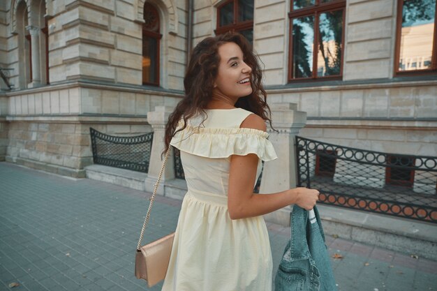 Portrait d'élégante femme brune souriante et heureuse marchant dans la rue