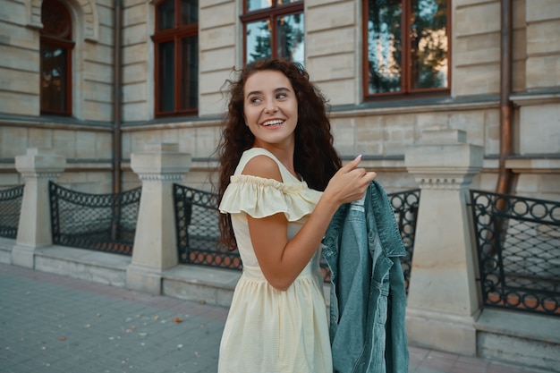 Portrait d'élégante femme brune souriante et heureuse marchant dans la rue