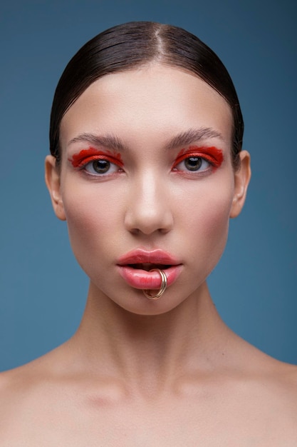 Portrait d'une élégante jeune femme au maquillage rouge vif sur fond bleu. Mode beauté