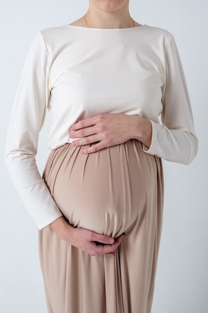 Portrait d'élégante jeune femme enceinte en robe beige