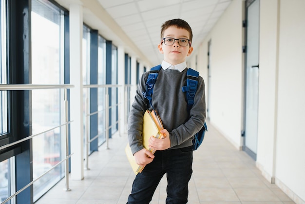 Portrait d'un élève heureux de l'école élémentaire Smart lunettes enfant debout à l'école Petit enfant tenant un livre