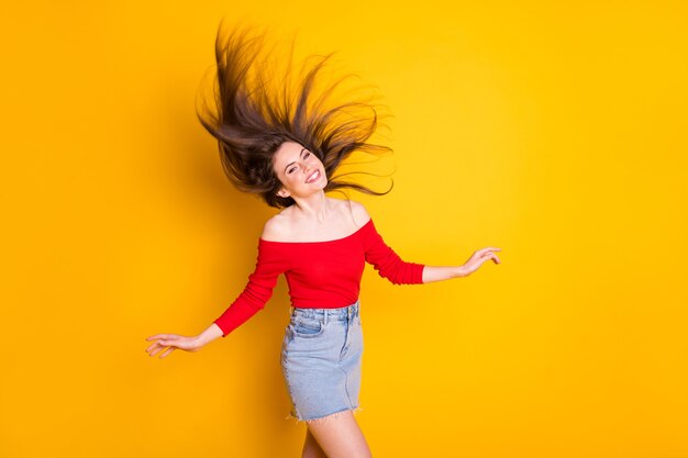 Portrait d'elle, elle est belle et gaie, jolie et gaie, une adolescente géniale et gaie, jetant des cheveux naturels sains s'amusant isolée sur fond de couleur jaune vif éclatant et éclatant