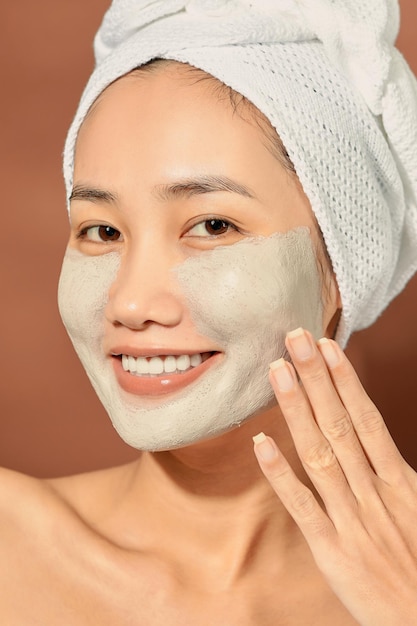 Portrait émotionnel d'une belle jeune femme nue heureuse et positive avec un masque cosmétique d'argile sur son visage