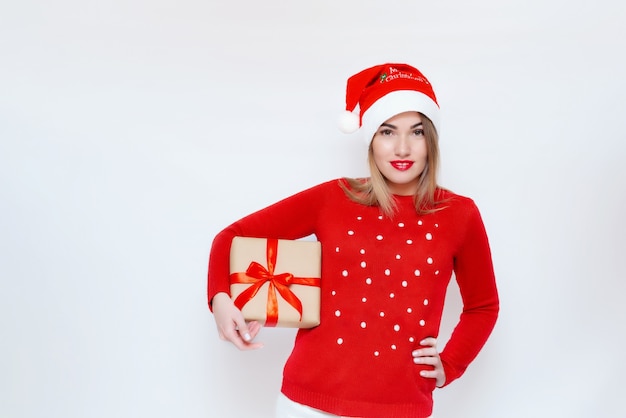 Portrait émotionnel d'une fille avec une boîte-cadeau dans ses mains dans un chapeau de Noël