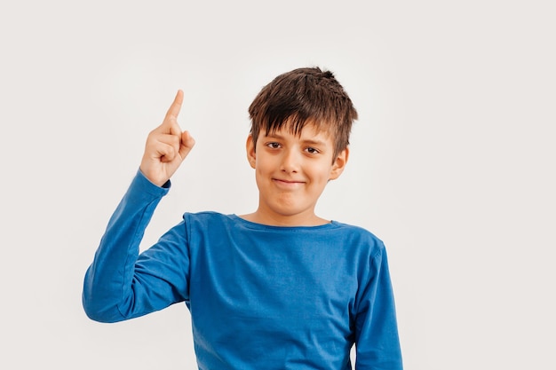 Portrait émotionnel mi-long d'un adolescent caucasien portant un t-shirt bleu. Adolescent surpris regardant la caméra. Bel enfant heureux, isolé sur fond blanc.