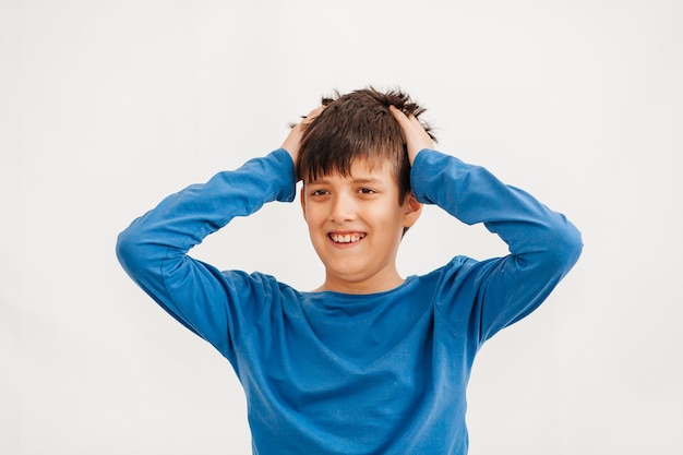 Portrait émotionnel mi-long d'un adolescent caucasien portant un t-shirt bleu. Adolescent surpris regardant la caméra. Bel enfant heureux, isolé sur fond blanc.