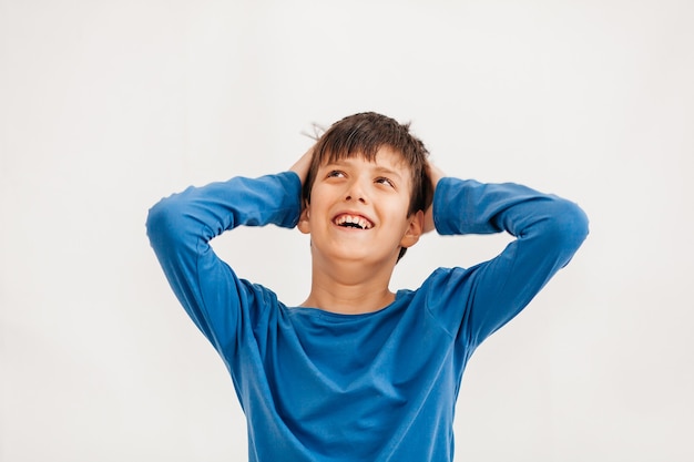 Portrait émotionnel mi-long d'un adolescent caucasien portant un t-shirt bleu. Adolescent surpris regardant la caméra. Bel enfant heureux, isolé sur fond blanc.