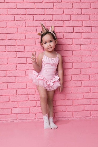 portrait émotionnel d'une petite fille asiatique dans un costume de ballerine costumes sur fond rose