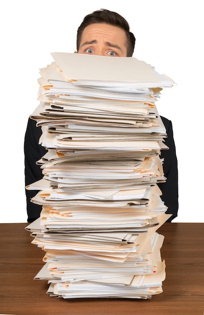 Portrait d'un employé inquiet derrière une pile de documents