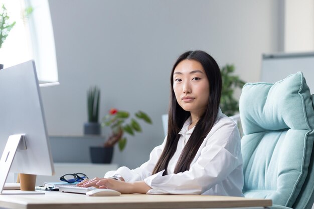 Portrait d'une employée de bureau asiatique réussie femme d'affaires travaillant à l'ordinateur en regardant