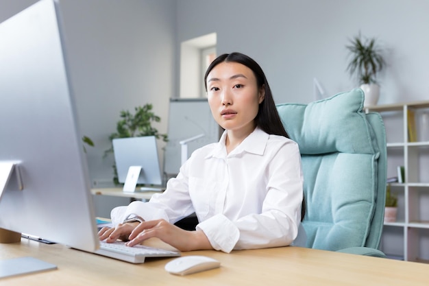 Portrait d'une employée de bureau asiatique réussie femme d'affaires travaillant à l'ordinateur en regardant