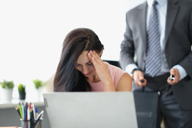 Portrait d'une employée de bureau fermant le visage se sentant honteuse à cause du harcèlement de son patron. Homme debout derrière avec décompresser la ceinture. Harcèlement au travail