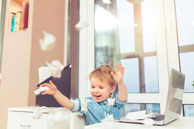 Portrait d'enfant d'affaires au bureau jouant avec des documents. Enfant d'affaires confiant réussi