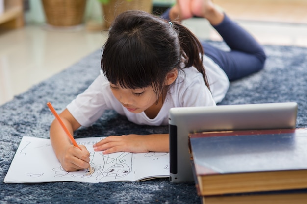 Portrait d'un enfant d'âge préscolaire utilisant une tablette pour ses devoirs, mise au point douce de l'enfant faisant ses devoirs à l'aide d'une tablette numérique recherchant des informations sur Internet, l'apprentissage en ligne ou le concept d'enseignement à domicile