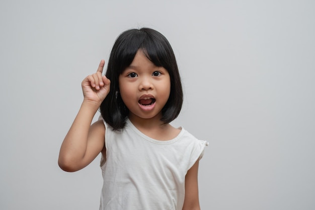 Portrait d'enfant asiatique de 5 ans et pour ramasser les cheveux et placer ses mains sur son menton faire réfléchir