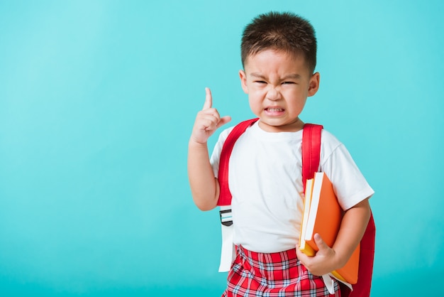 Portrait enfant asiatique garçon face à des livres étreignant sérieusement penser et pointer du doigt l'espace