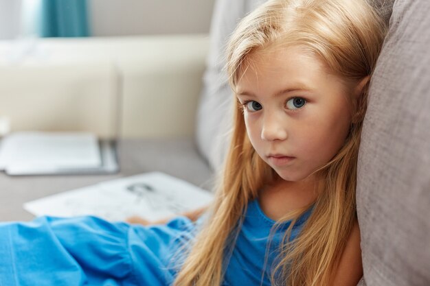 Photo portrait d'enfant caucasien fille en robe assis sur un canapé dans la vie