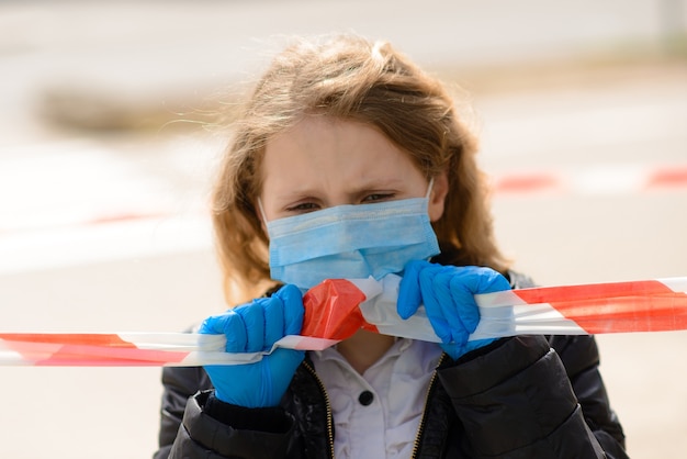 Portrait d'enfant caucasien triste en masque facial sur une aire de jeux fermée en plein air.