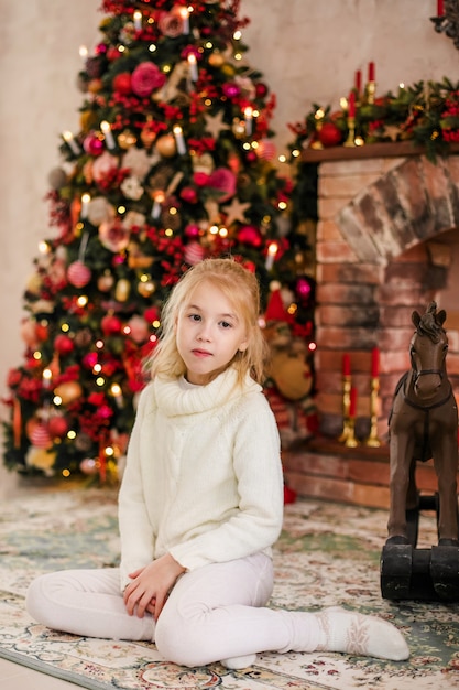 portrait d&#39;enfant fille blonde heureuse en pull blanc, implantation sur le sol