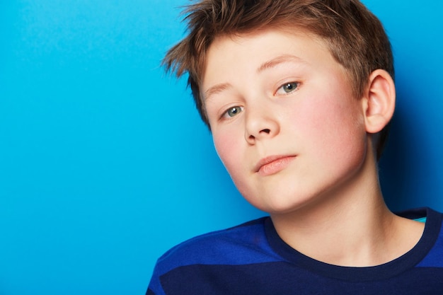 Portrait d'enfant et fond bleu avec des jeunes élégants et des vêtements à la mode dans un studio Jeune garçon enfant et visage avec confiance et étudiant avec un style moderne et décontracté avec modèle relax