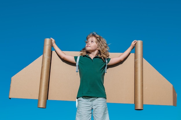 Portrait d'enfant garçon avec des ailes de jouet sur fond de ciel d'été pour les enfants leader du succès et gagnant co