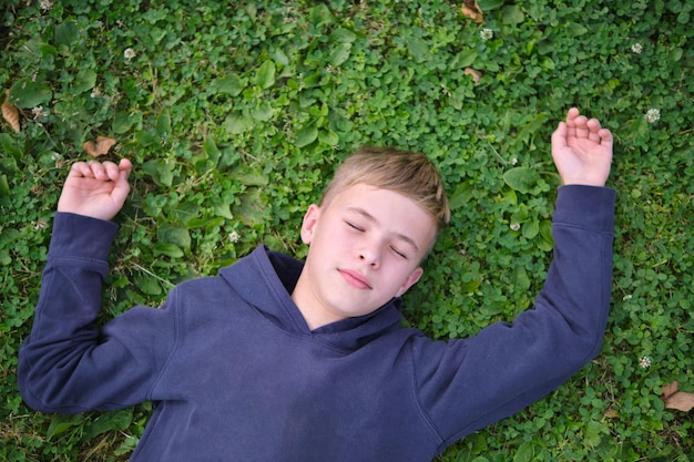 Portrait d'enfant garçon à l'extérieur reposant sur la pelouse d'herbe