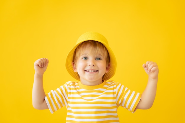 Portrait d'enfant heureux contre le mur jaune en vacances d'été.