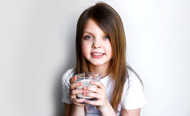 Portrait d'un enfant heureux souriant gaiement avec un verre de lait