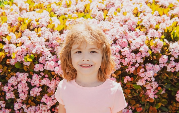 Portrait d'enfant joyeux sur fond de parc de printemps en fleurs mignon petit garçon joyeux enfant