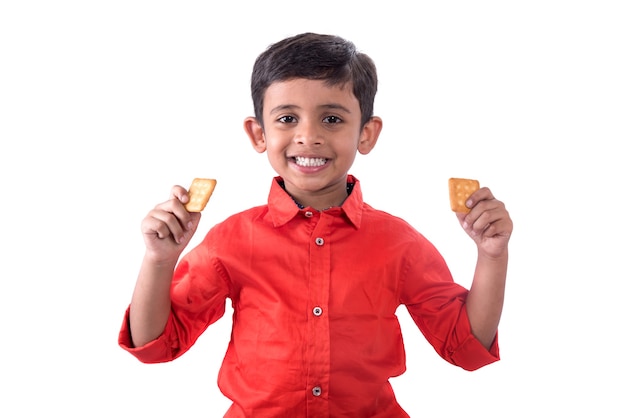 Portrait d'enfant mangeant un biscuit sur mur blanc