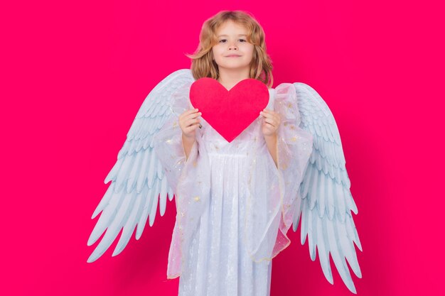 Portrait d'enfant mignon avec des ailes d'ange isolé sur fond de studio rouge Petit ange saint valentin Enfants angéliques