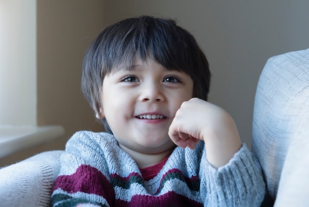 Portrait d'enfant positif assis sur un canapé