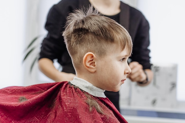 Portrait d'un enfant de sexe masculin au salon de coiffure pour se couper les cheveux Petit garçon se fait couper les cheveux dans un salon de coiffure