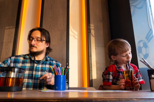 Portrait d'enfant avec son père dessinant avec des crayons au café
