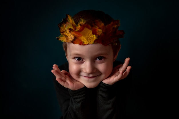 Portrait d'un enfant souriant avec une couronne de feuilles