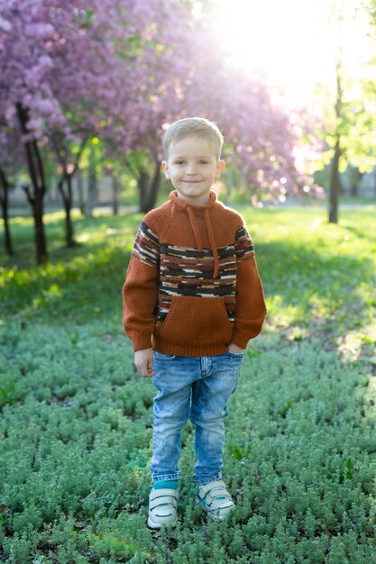 Portrait d'un enfant souriant (garçon heureux) sur le fond d'un arbre en fleurs au printemps.