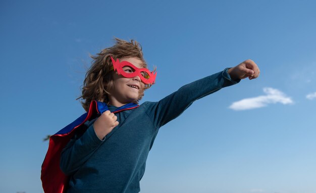 Portrait d'enfant de super-héros contre l'espace de copie de fond de ciel bleu