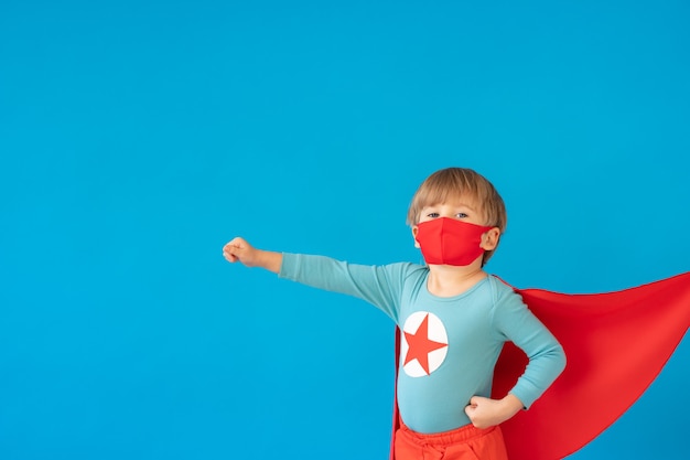 Portrait d'enfant de super héros contre le mur de papier bleu.