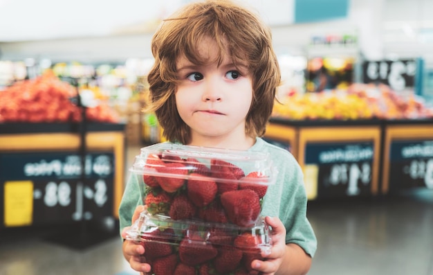 Portrait d'enfant tenant des fraises à l'épicerie au supermarché Légumes et fruits biologiques frais dans le rayon épicerie du magasin d'alimentation ou du supermarché pour enfant