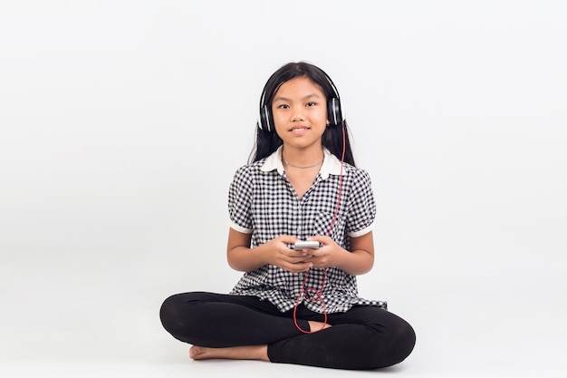 Portrait d'enfants asiatiques fille assise à écouter de la musique isolée