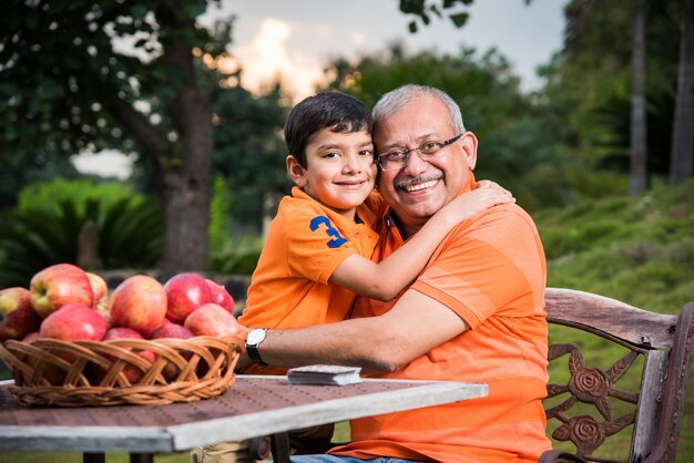 Portrait d'enfants asiatiques indiens heureux et grand-père assis sur une chaise de jardin