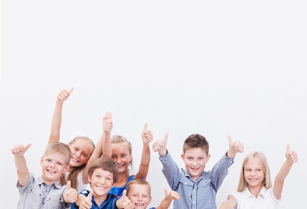 Portrait d'enfants heureux montrant le geste du pouce vers le haut, sur fond blanc