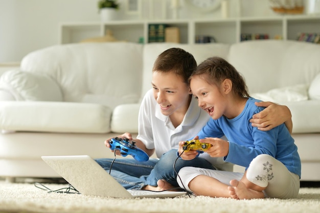 Portrait d'enfants jouant à des jeux informatiques, à la maison