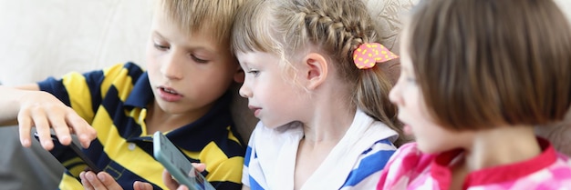 Portrait d'enfants jouant sur un téléphone portable, les enfants passent du temps amusant ensemble assis sur des