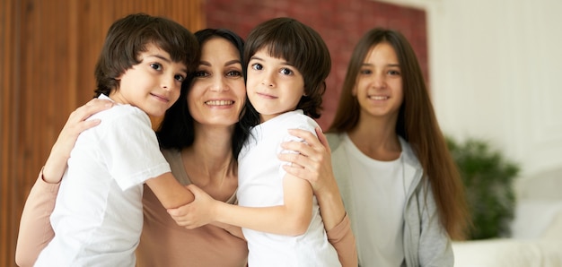 Portrait d'enfants latins mignons petits garçons jumeaux regardant la caméra et étreignant leur maman