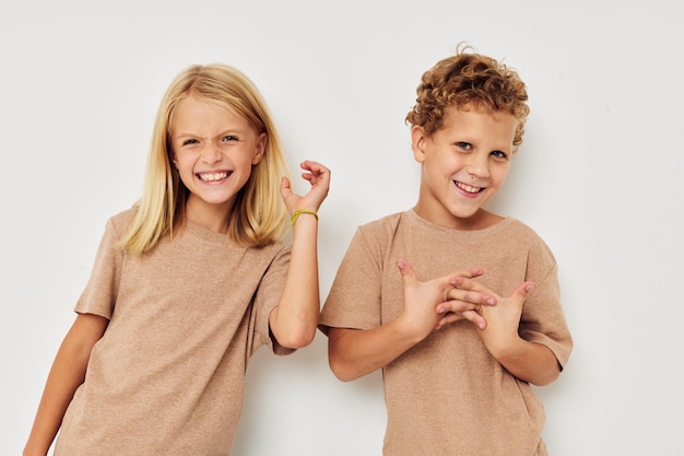 Portrait d'enfants mignons en t-shirts beiges posant pour s'amuser fond isolé